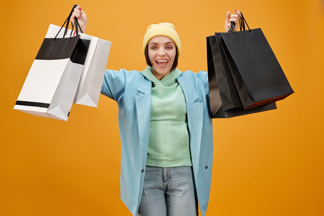 Smiling woman holding shopping bags against a bright yellow background, perfect for e-commerce and marketing.