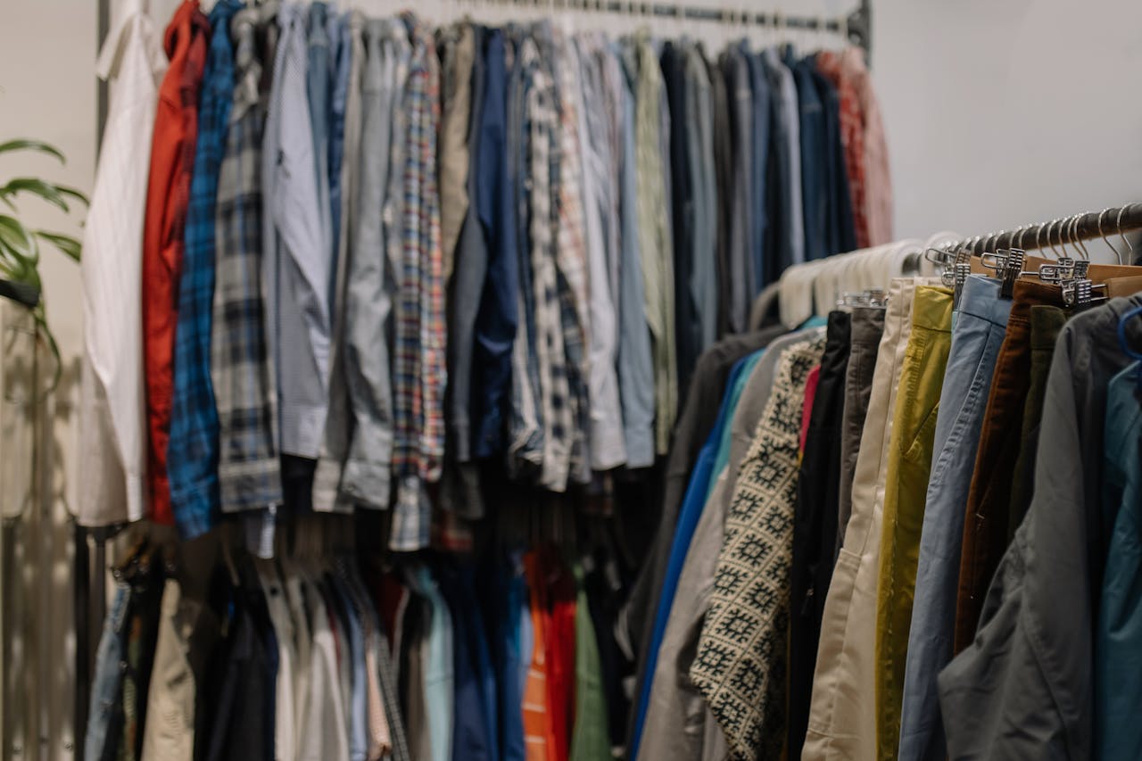 Assorted clothing on racks in a thrift shop, showcasing various styles and colors.